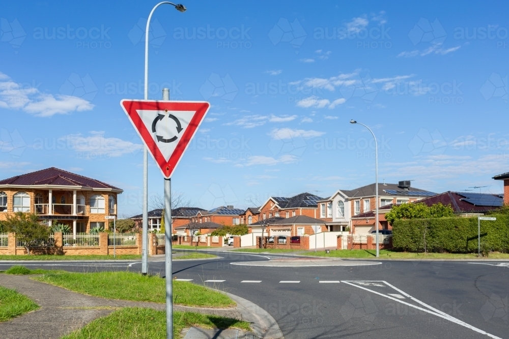 roundabout sign before road intersection in suburbia - Australian Stock Image