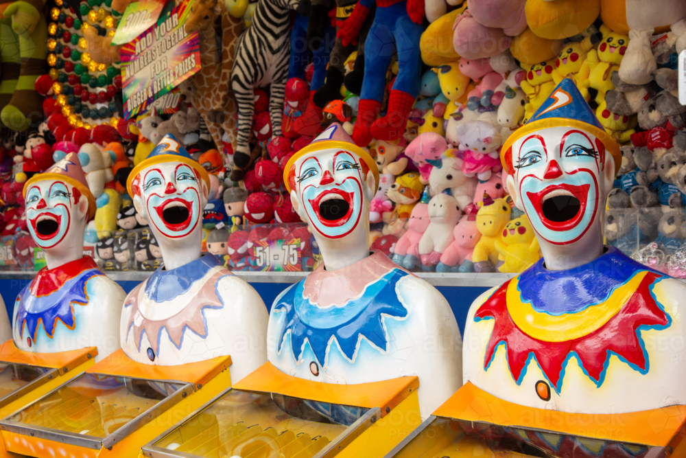 Row of brightly coloured clown heads turning at country show - Australian Stock Image