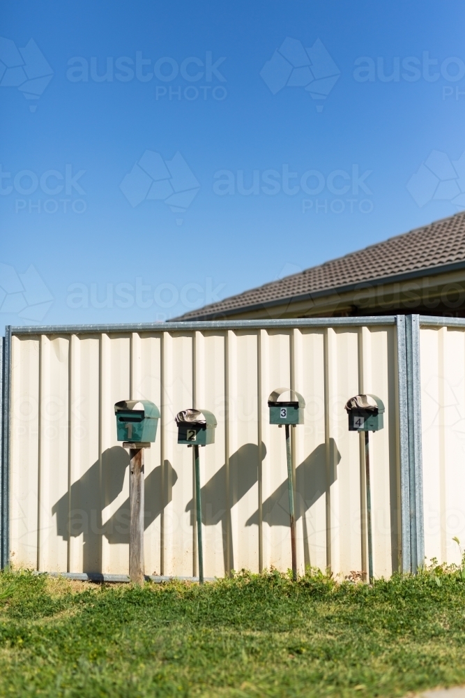 row of mailboxes against a cream coloured fence - Australian Stock Image