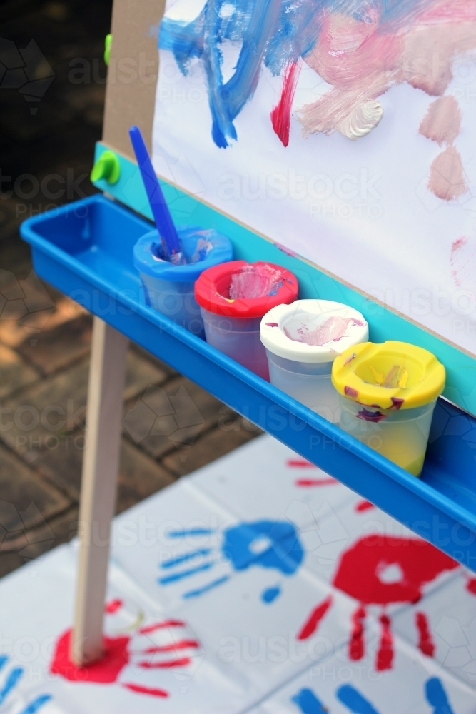 Row of paint pots on easel with mess mat - Australian Stock Image