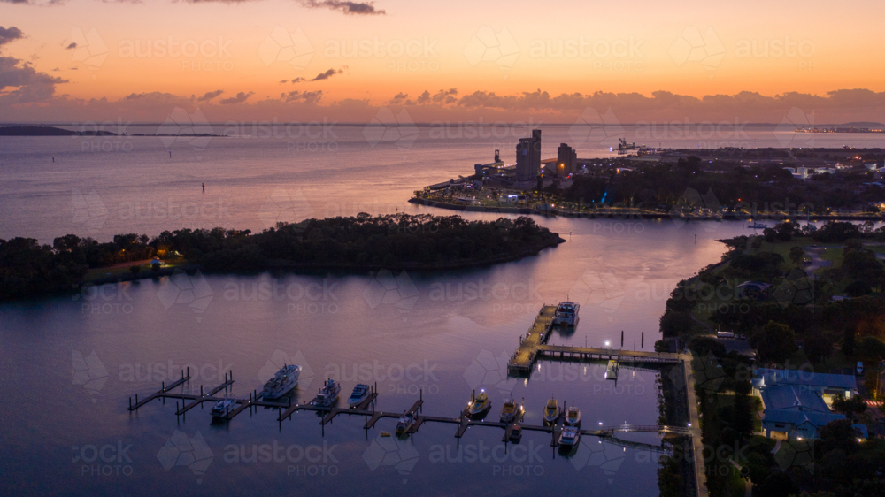 Rows of yachts and boats moored along illuminated piers at dusk - Australian Stock Image