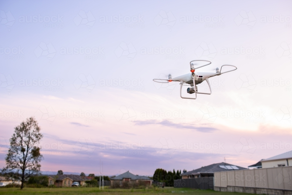 RPA drone flying over edge of suburban area at dusk - Australian Stock Image