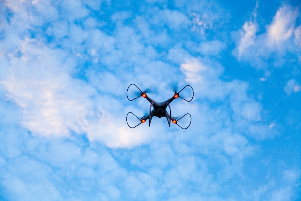 RPA drone hovering in clouded sky at dusk - Australian Stock Image