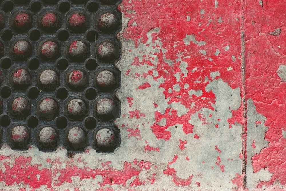 rubber mat on concrete with red flaking paint - Australian Stock Image