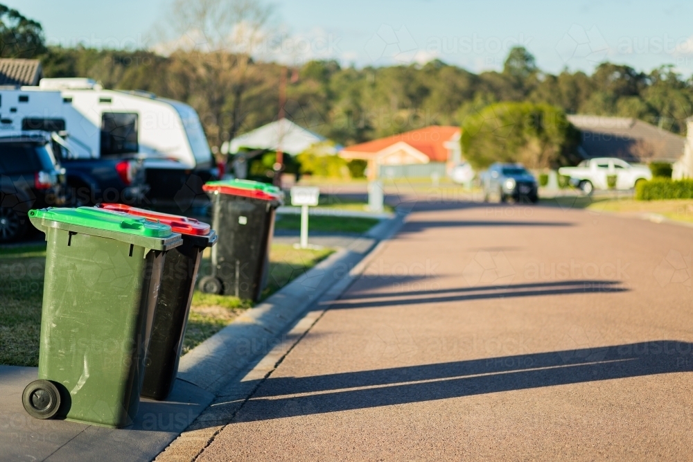 Rubbish and green bins out on quiet town street awaiting collection - Australian Stock Image