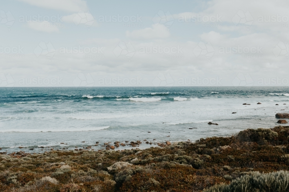 Rugged coast with long waves on sunny day - Australian Stock Image