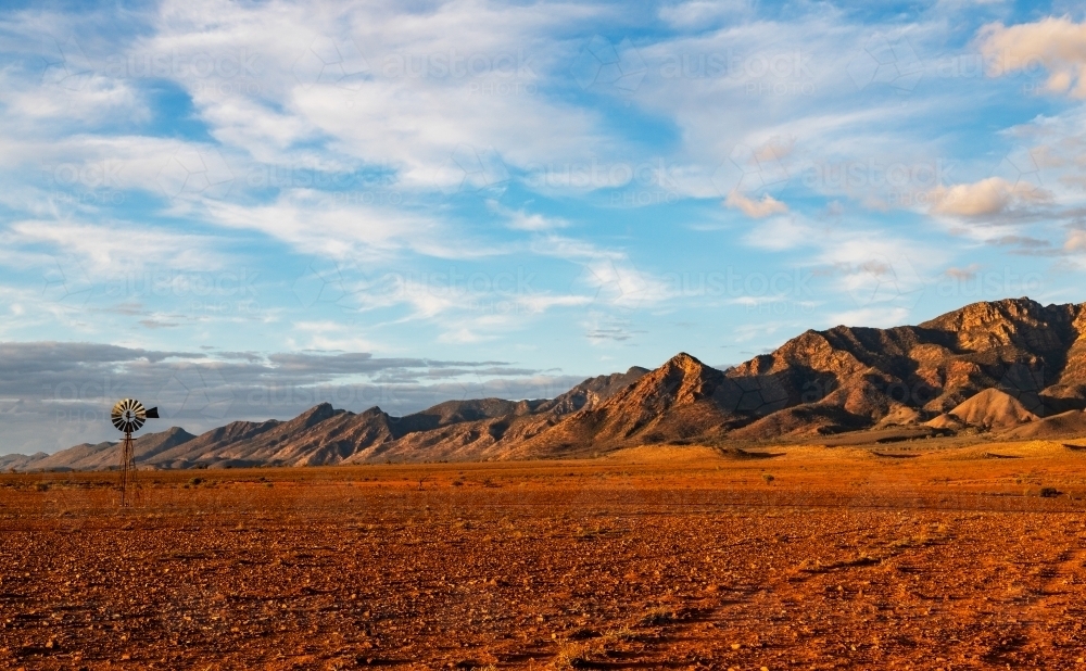 rugged ranges and windmill in late afternoon light - Australian Stock Image