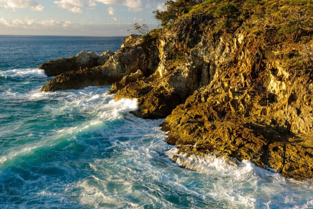 Rugged rocky cliffs and surf in the early morning light - Australian Stock Image