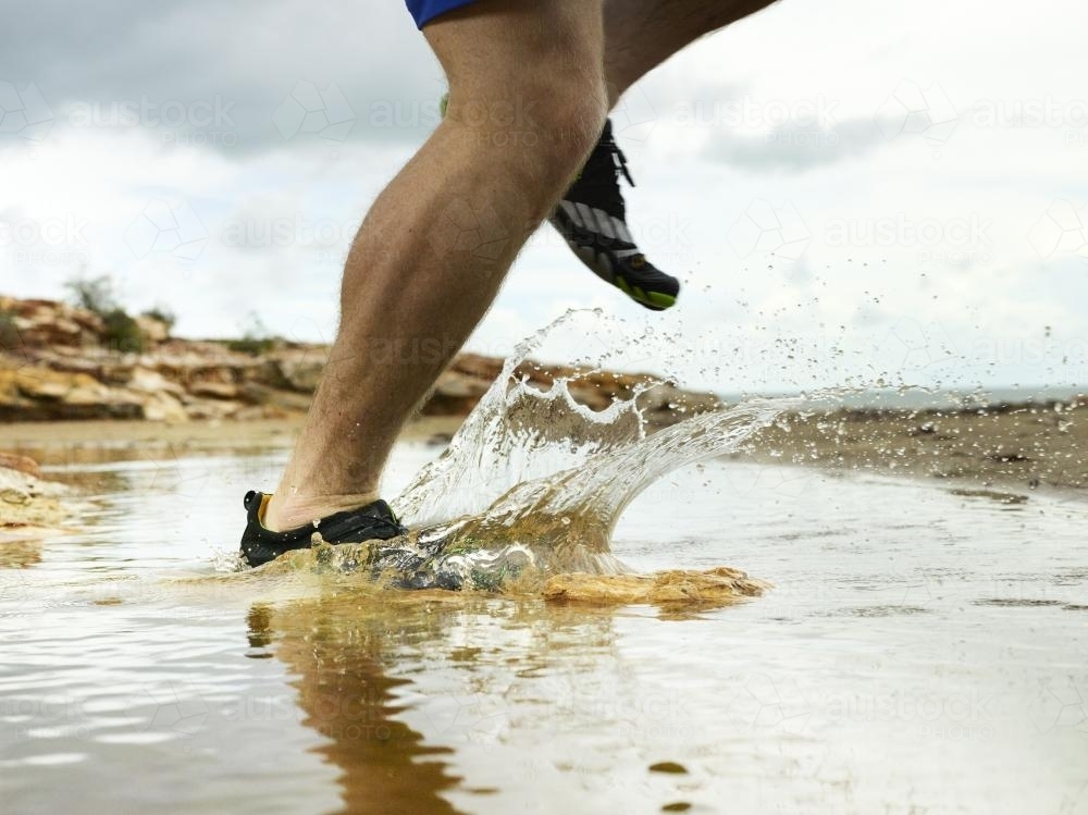 Running through a puddle and splashing at the beach - Australian Stock Image