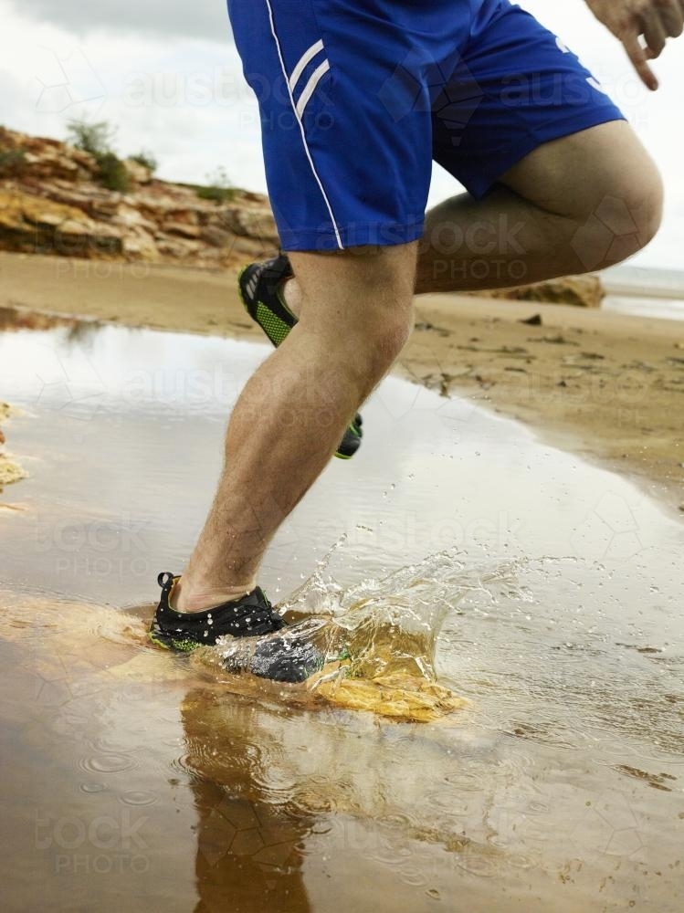 Running through a puddle and splashing at the beach - Australian Stock Image