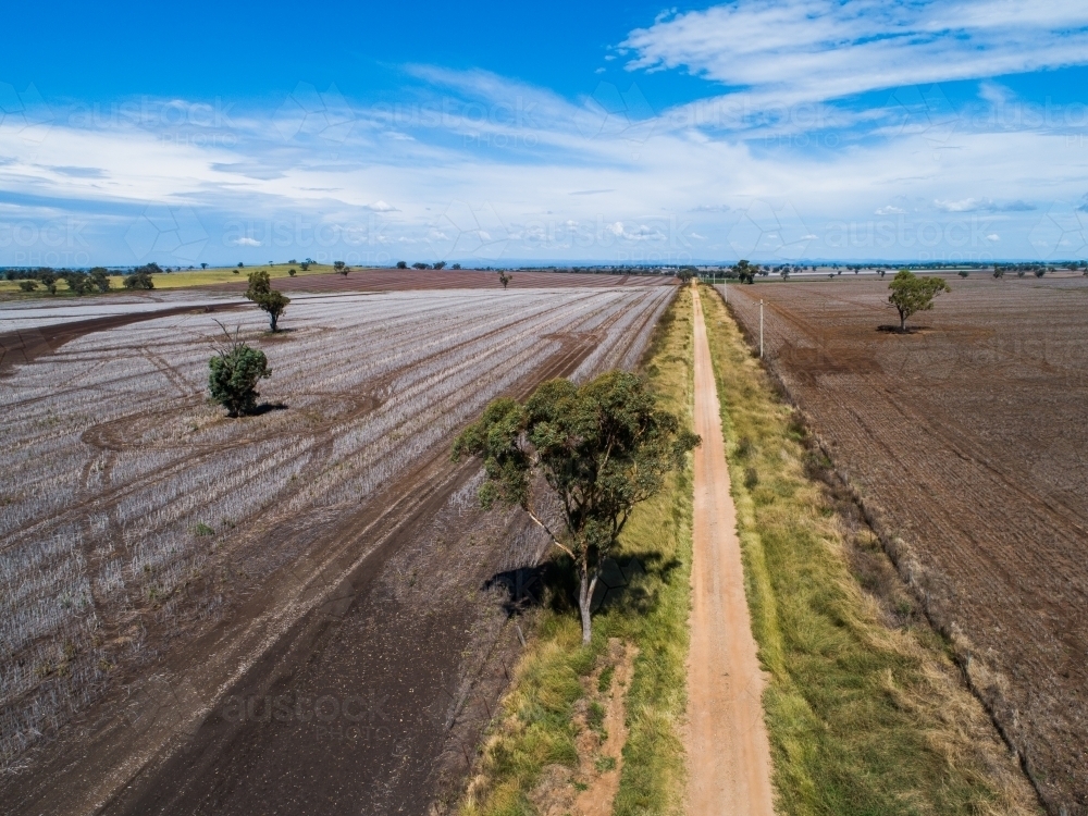 Rural aerial view in NSW Australia of harvested farm paddocks and dirt road - Australian Stock Image