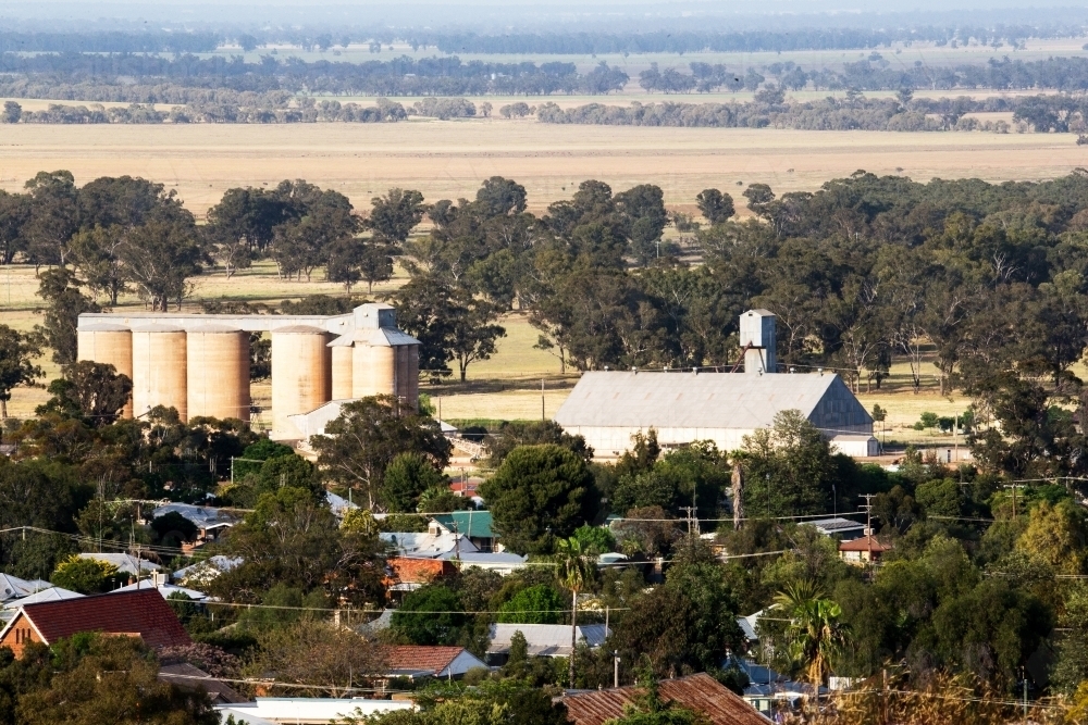 Rural area with a big field and a community with houses, trees and silos and storage shed - Australian Stock Image