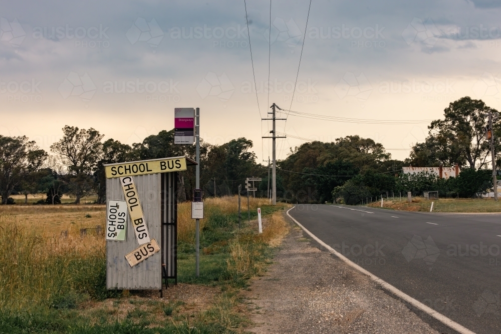 Rural bus stop on the roadside in country Victoria covered in signs - Australian Stock Image