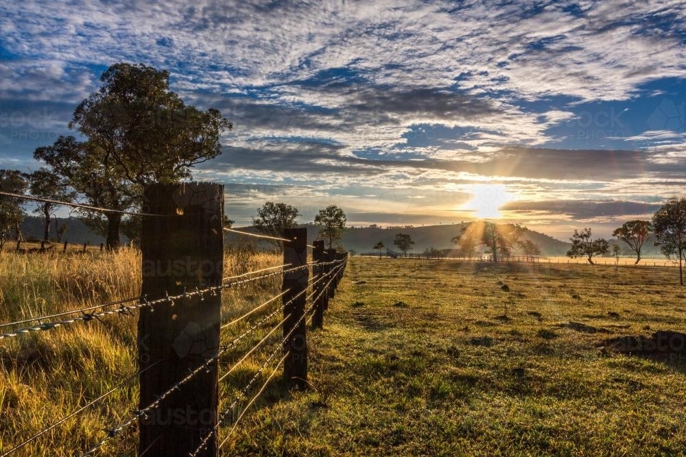 Rural farm fence leading to sunrise - Australian Stock Image