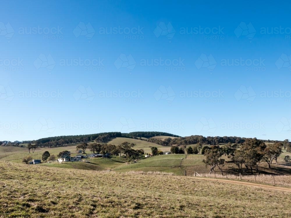 Rural farm in rolling hills and a big blue sky - Australian Stock Image