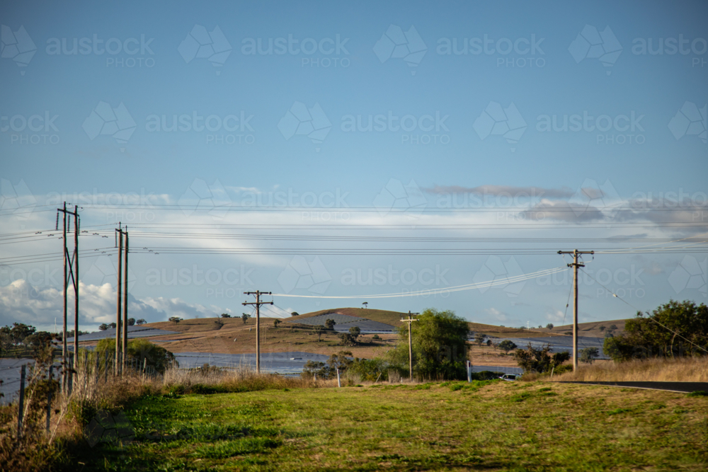 Rural landscape with power lines and solar farm under a vast blue sky - Australian Stock Image