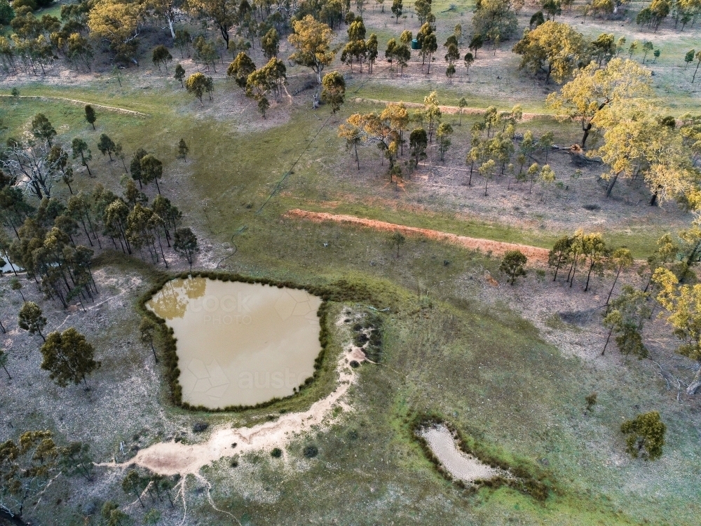 Rural paddock with large dam full of muddy water and small dry empty dam - Australian Stock Image