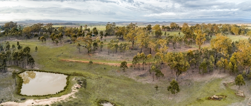 Rural paddock with large dam full of muddy water and small dry empty dam - Australian Stock Image