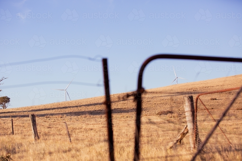Rural Wind Turbines in a farm setting with a paddock gate in the foreground - Australian Stock Image