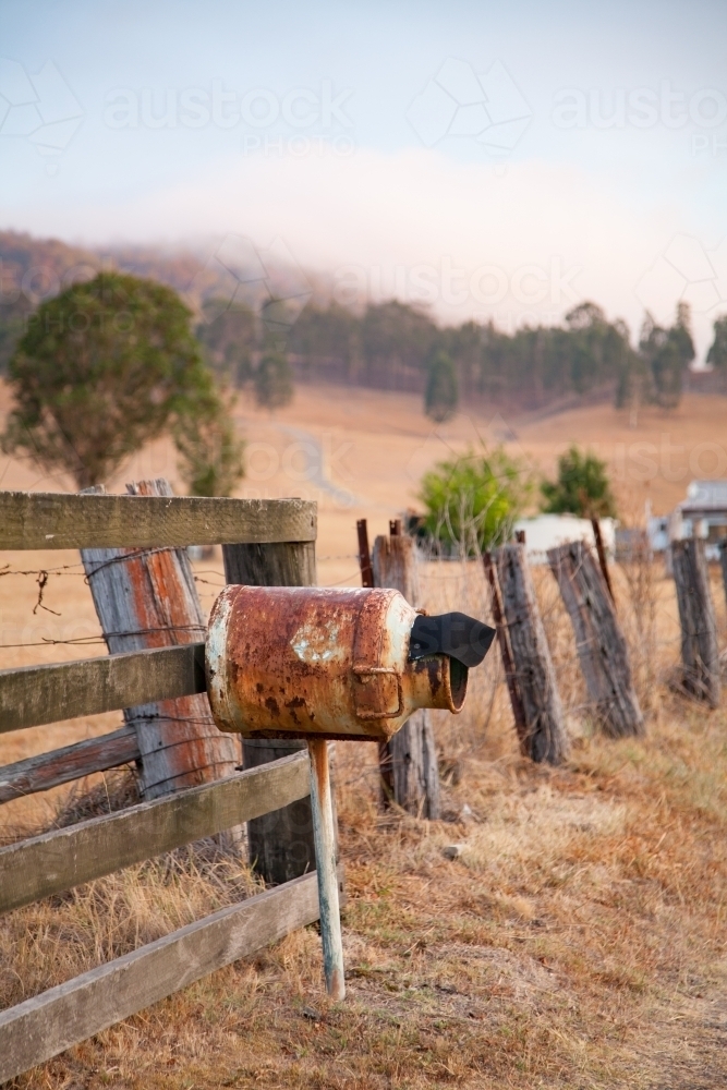 Rusted mailbox made out of milk can beside rural fence - Australian Stock Image