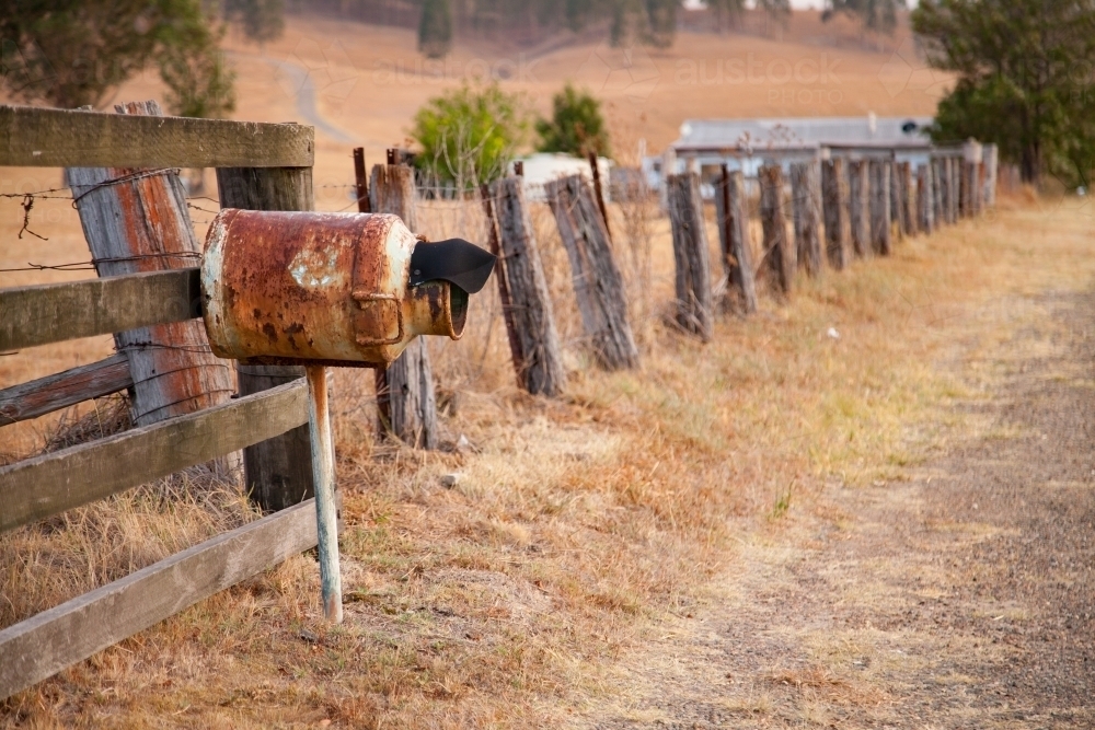Rusted mailbox made out of milk can beside rural fence - Australian Stock Image