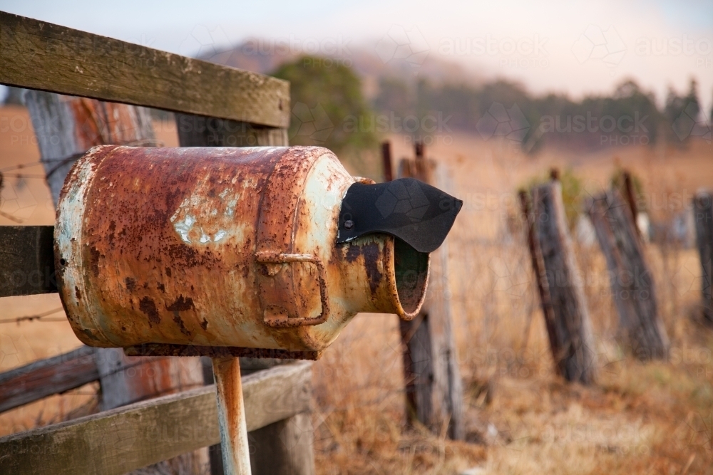 Rusted mailbox made out of milk can beside rural fence - Australian Stock Image