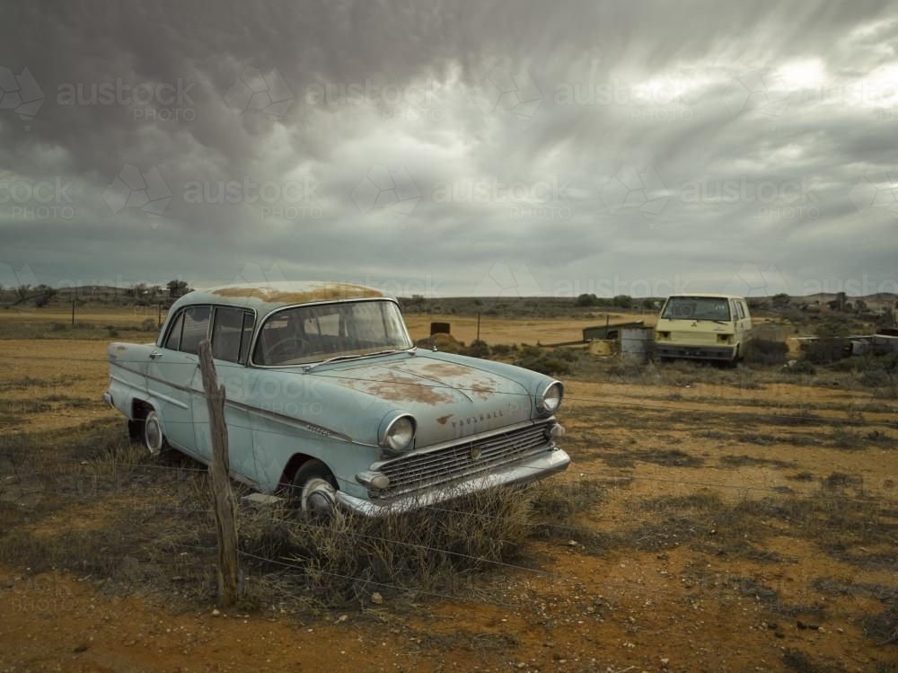 Rusted out blue car in the outback against dramatic sky - Australian Stock Image