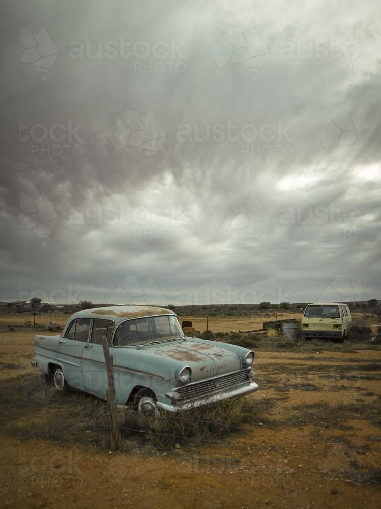 Rusted out blue car in the outback against dramatic sky - Australian Stock Image