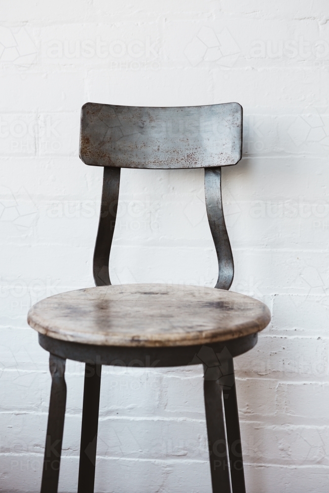 Rustic cafe chair against painted white brick wall - Australian Stock Image