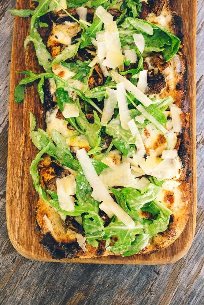 rustic pizza with rocket and parmesan - Australian Stock Image