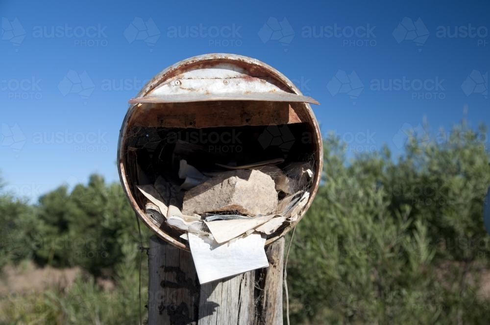 Rustic roadside mailbox with tree and blue sky background - Australian Stock Image