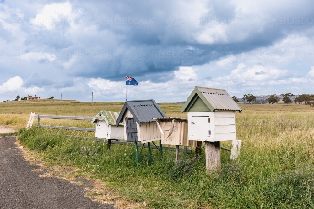 Rustic roadside mailboxes in remote area of country New South Wales with Australian flag flying - Australian Stock Image