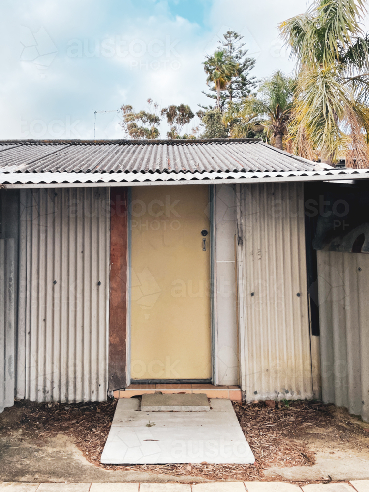 Rustic shed style housing with door and overcast sky and tree - Australian Stock Image