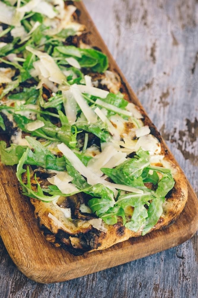 rustic vegetarian pizza with mushroom and rocket leaves - Australian Stock Image