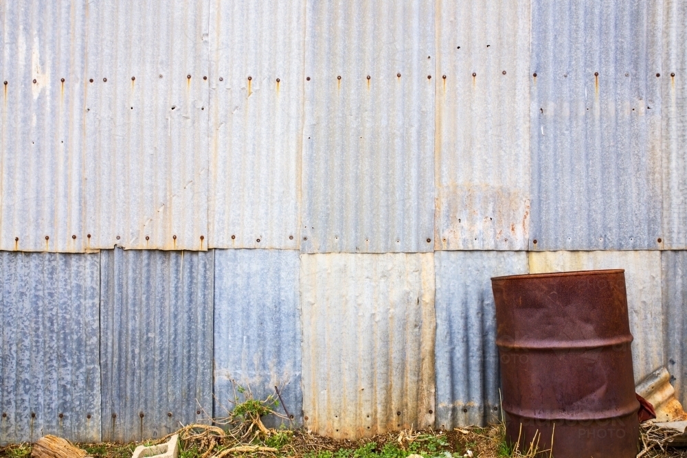 Rusty drum in front of corrugated iron wall - horizontal - Australian Stock Image