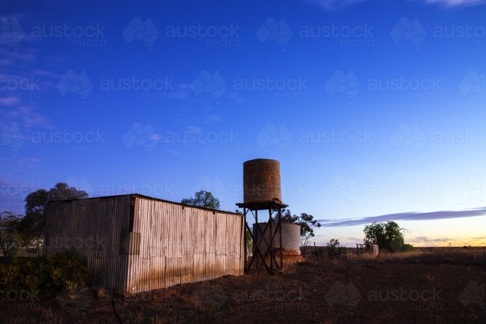 rusty old shed and tank at twilight - Australian Stock Image