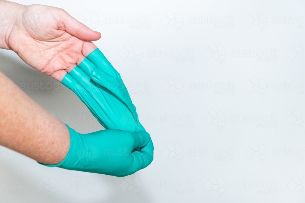 Safely removing green surgical gloves - Australian Stock Image