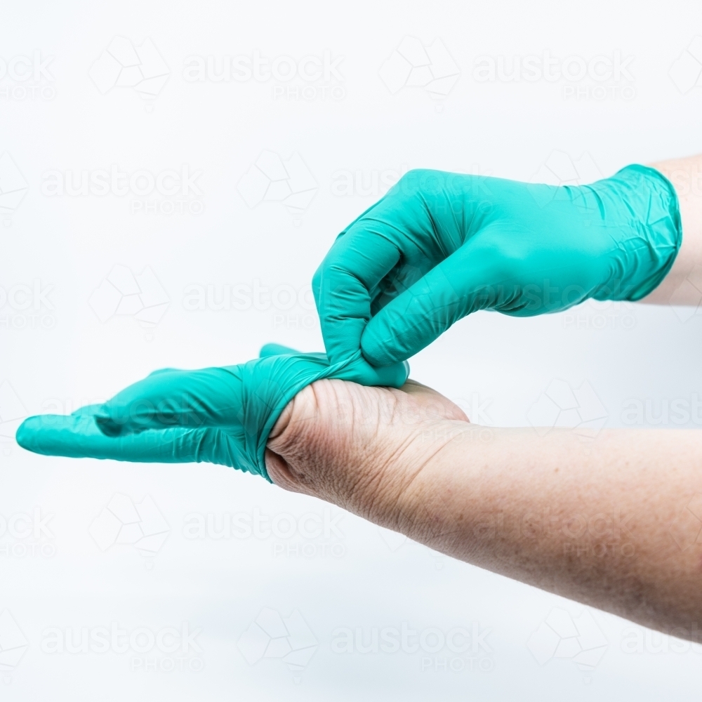 Safely removing green surgical gloves - Australian Stock Image