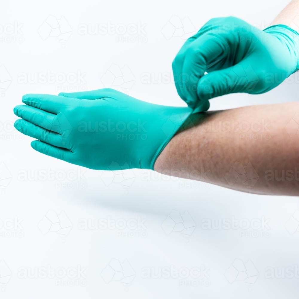 Safely removing green surgical gloves - Australian Stock Image