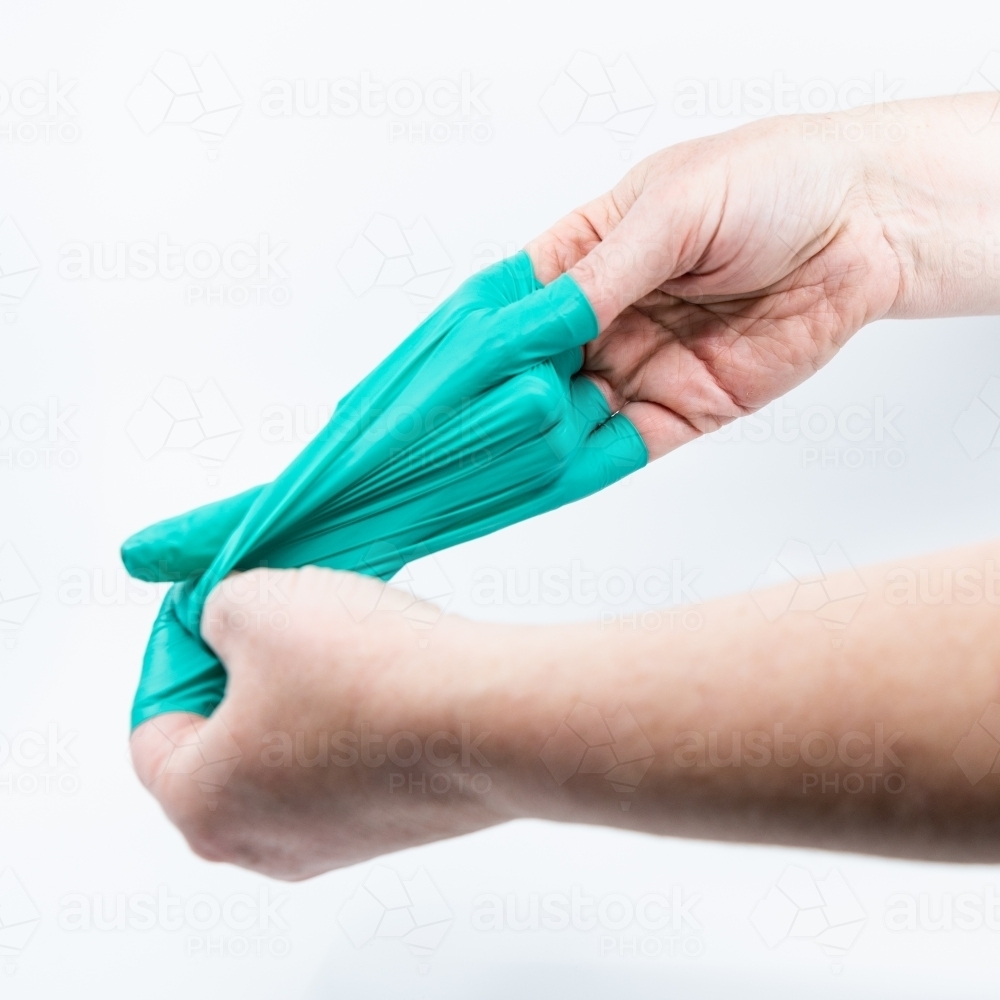 Safely removing green surgical gloves - Australian Stock Image