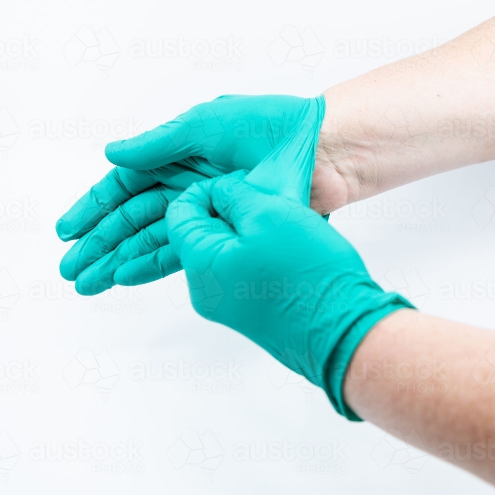 Safely removing green surgical gloves - Australian Stock Image