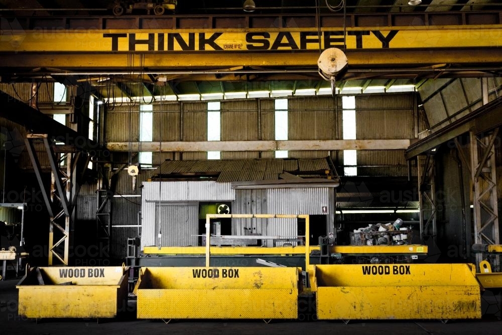 Safety sign, crane and wood boxes in a disused factory - Australian Stock Image