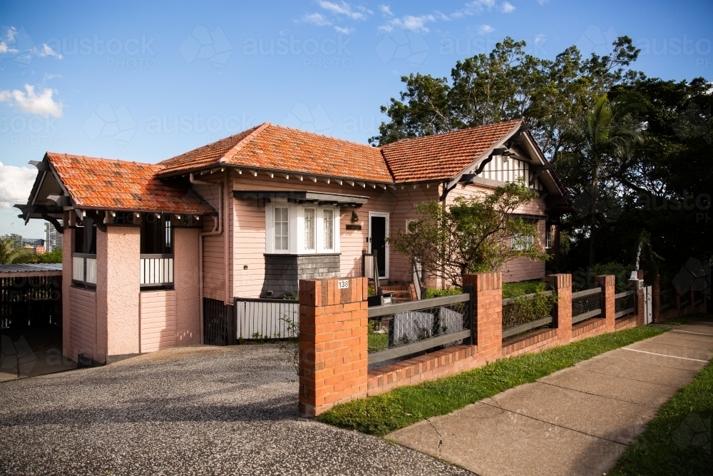 salmon pink house with red tile roof on a sunny day in Brisbane - Australian Stock Image