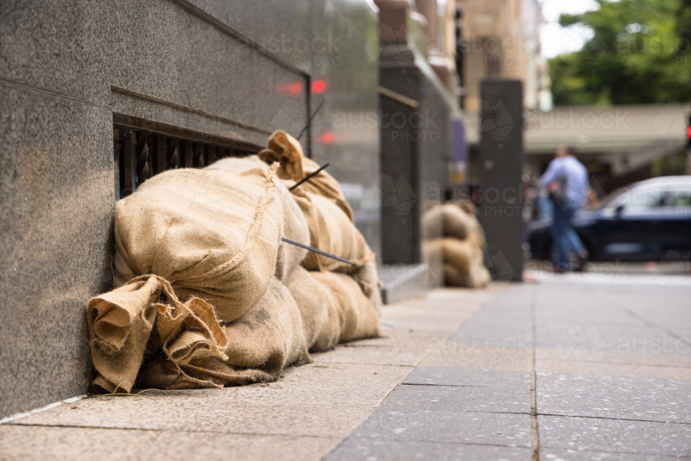 Sandbags along the footpath lining the lower windows of a building in Brisbane CBD before a cyclone - Australian Stock Image