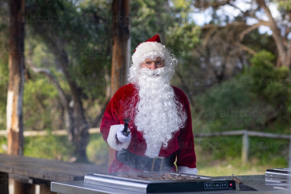 santa tending to the barbecue on an electric hotplate in a park - Australian Stock Image