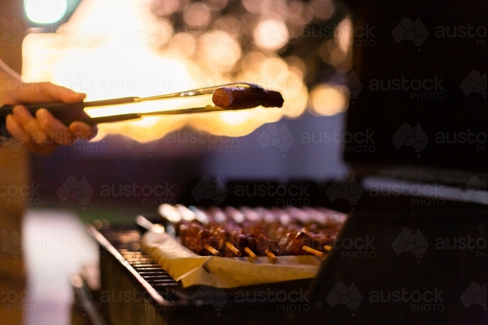 sausage in tongs at sunset - Australian Stock Image