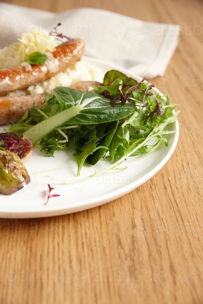 Sausage, mash potato and salad on plate - Australian Stock Image