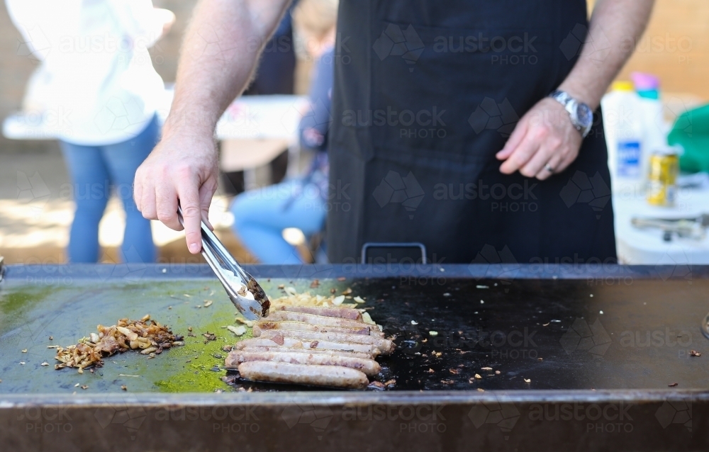 Sausages and onion cooking on a school fundraiser barbecue on election day - Australian Stock Image