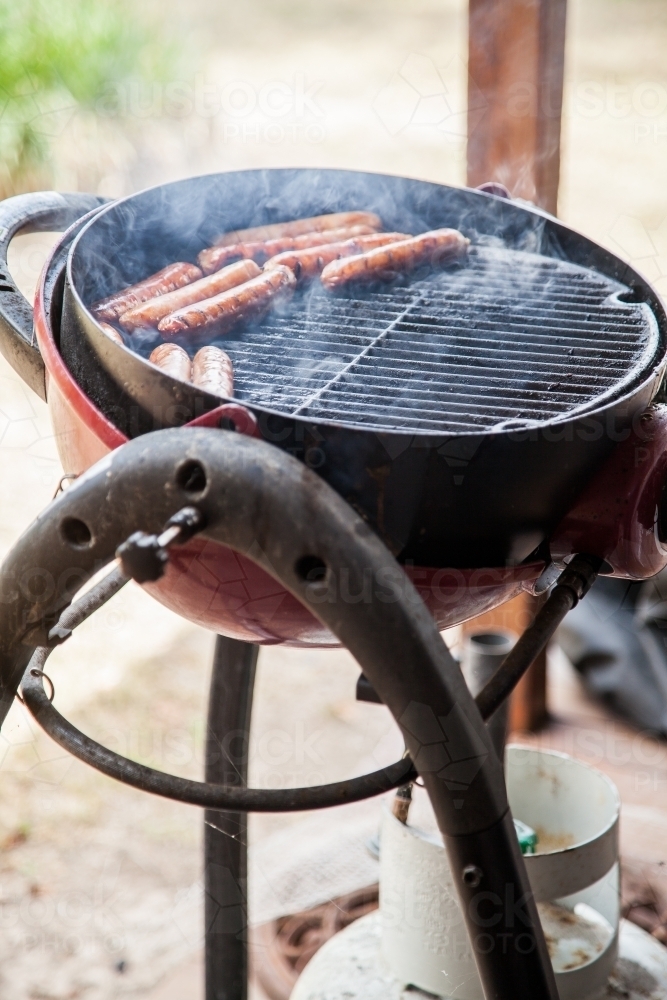 Sausages cooking on a portable backyard BBQ grill - Australian Stock Image