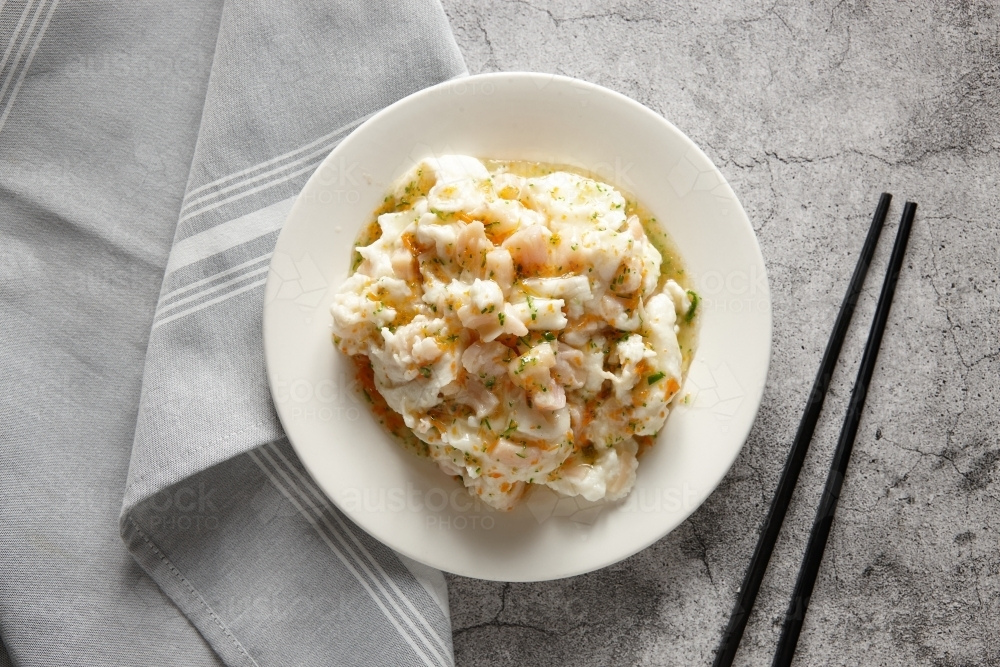 Scallop with egg white in a plate on a concrete surface with chopsticks - Australian Stock Image